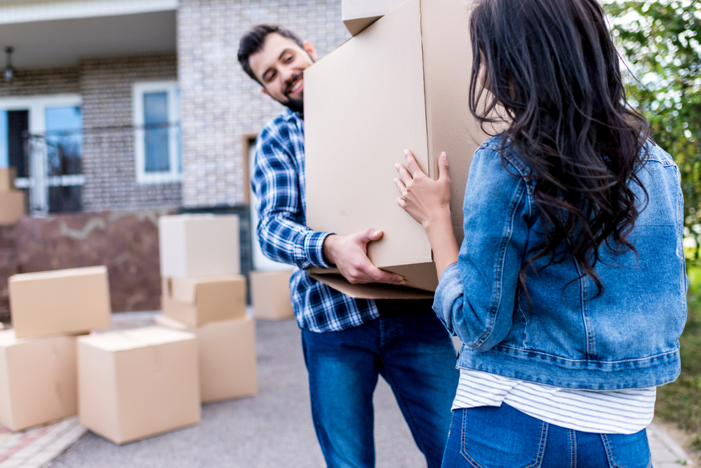 young couple carrying moving boxes into their new home