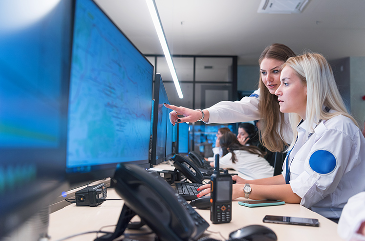 Security guard monitoring modern CCTV cameras in surveillance room. Two Female security guards in surveillance room.