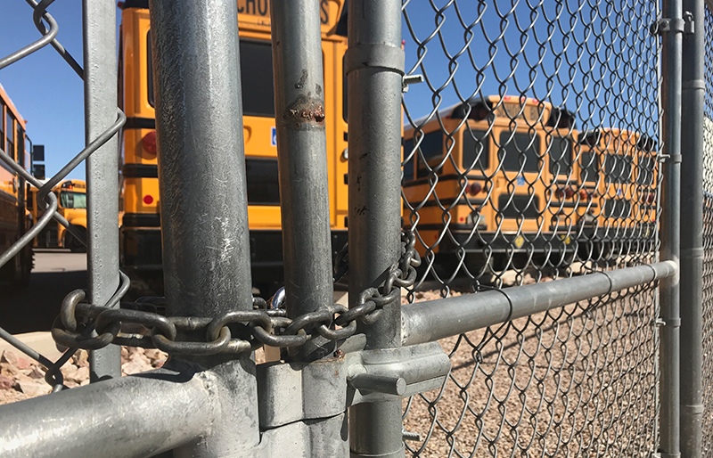School Buses Behind Chain Link Fence Protected by Security Cameras 24 hours
