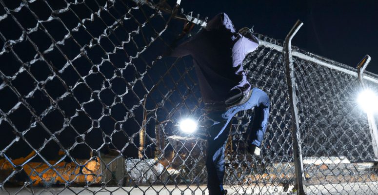 Burglar Climbing Over a St. Louis Business Commercial Chain Link Fence at Night